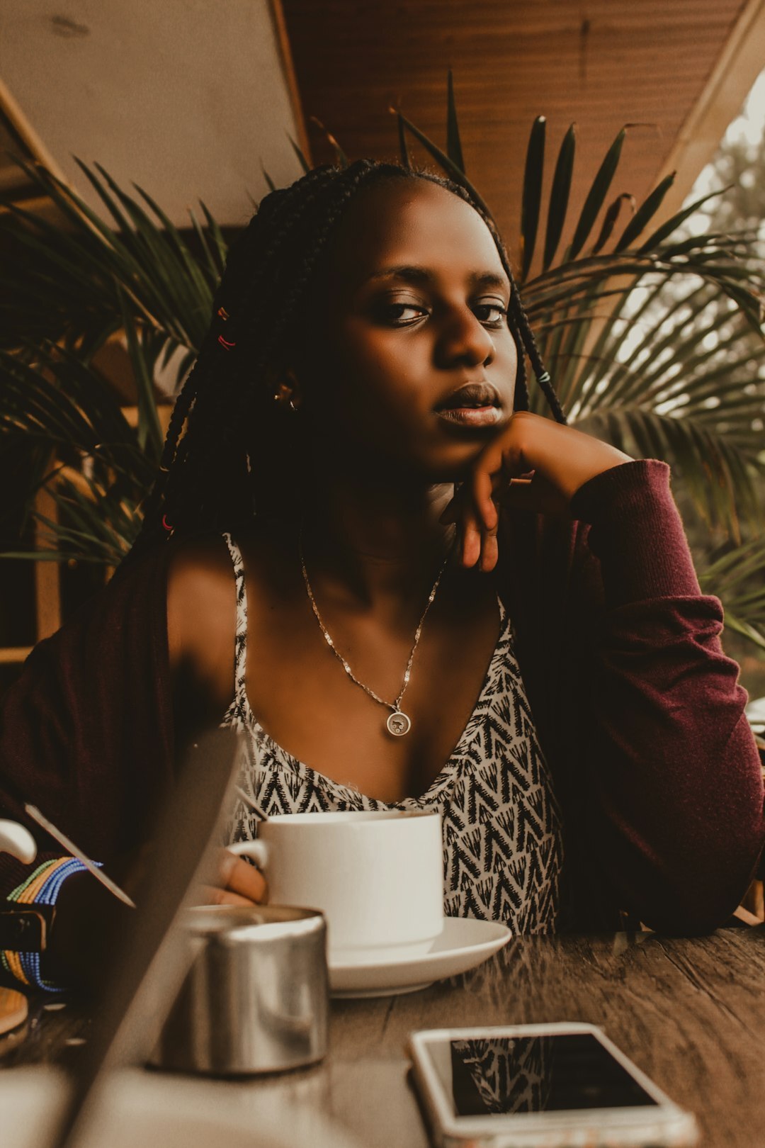 Brazilian woman sitting calmly while reflecting with a laptop nearby
